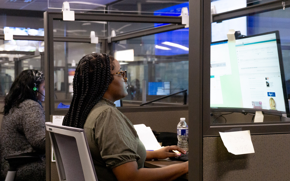 People working at computers inside an office with partitioned workstations
