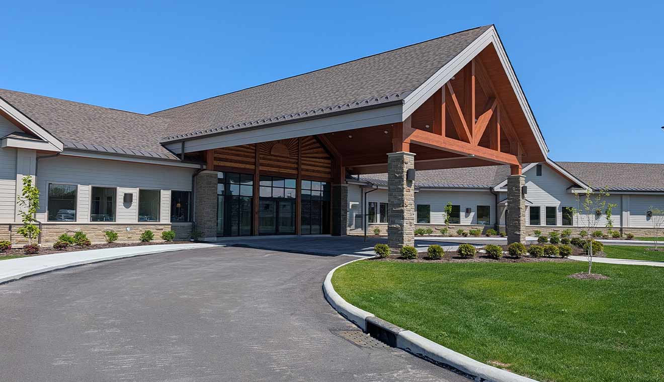 Exterior view of a modern senior living or healthcare facility with covered entrance driveway and landscaped grounds