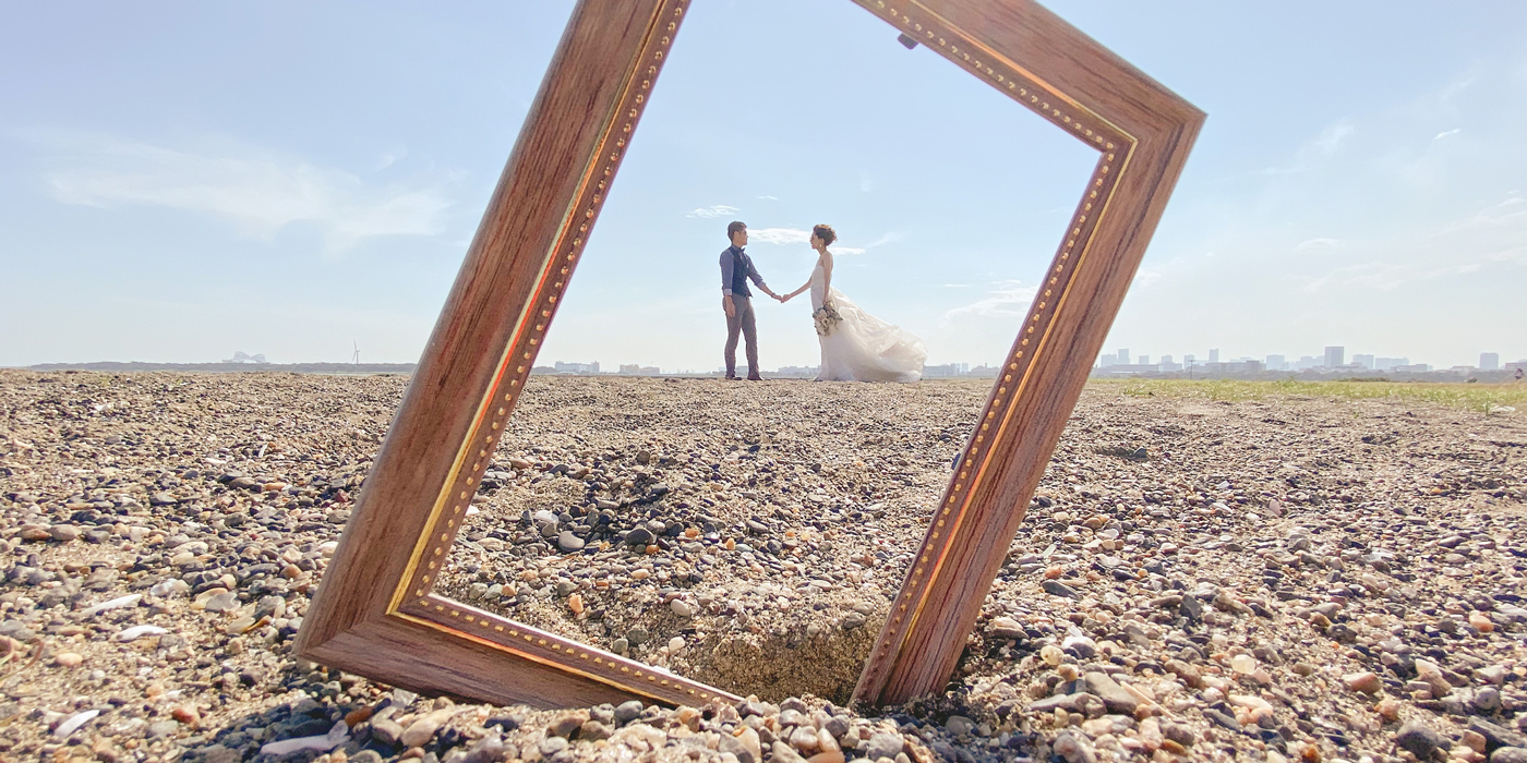 Wedding couple framed inside an empty picture frame on a beach