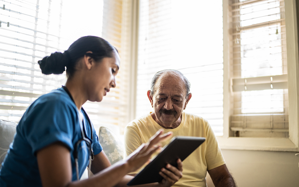 Healthcare worker showing information on a tablet to an older adult.