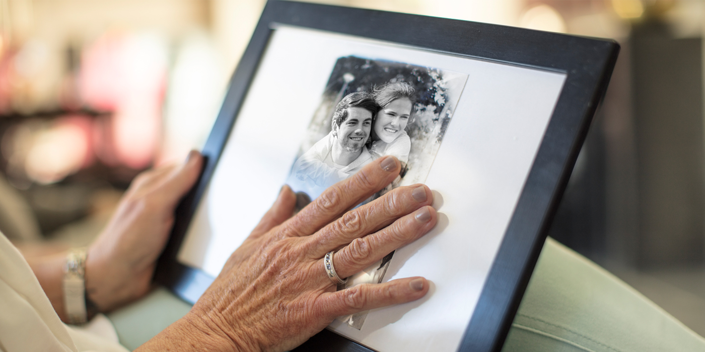 Person holding and touching a framed black-and-white photograph