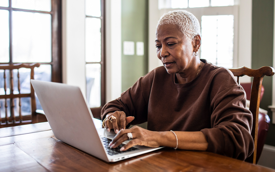 Older woman using a laptop at a dining table