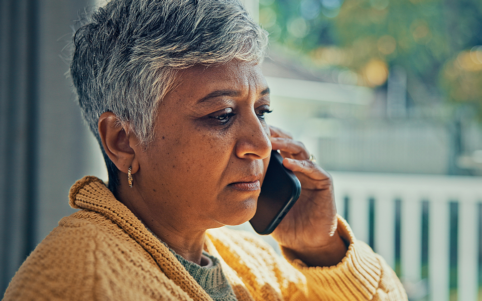 Person speaking on a phone while sitting indoors near a window