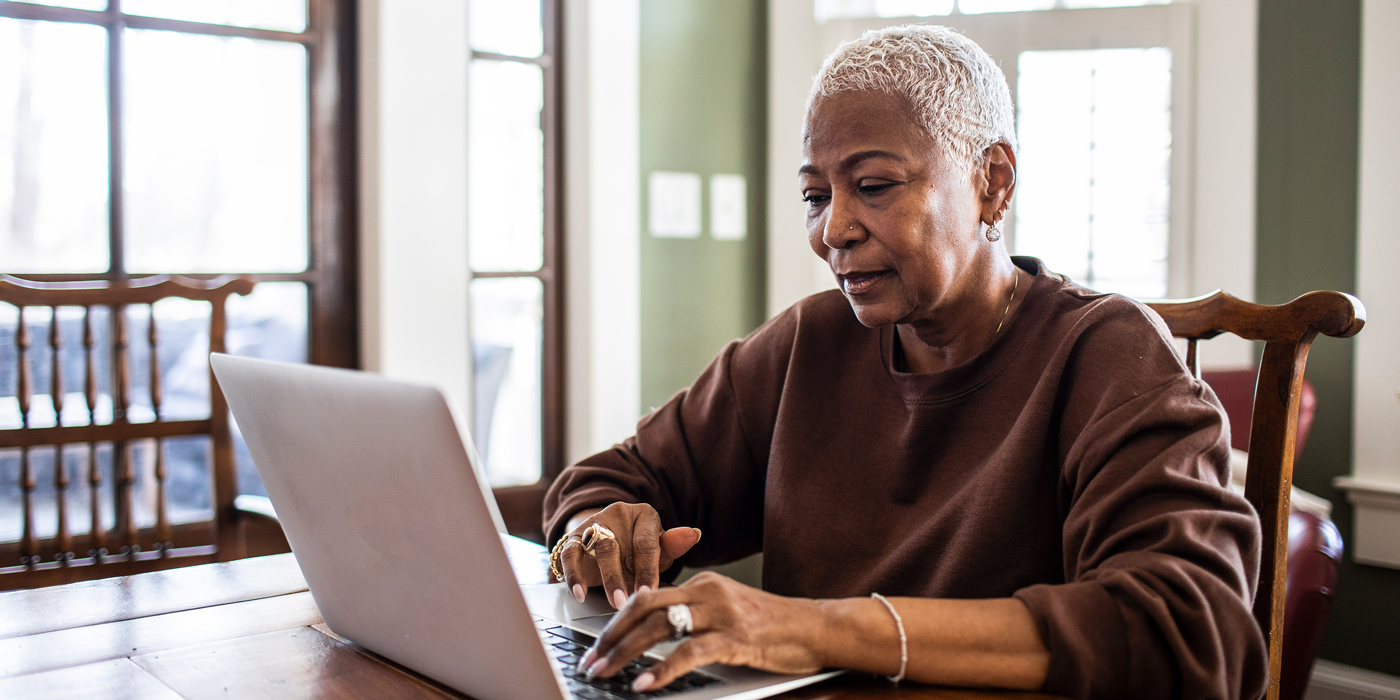 Older woman using a laptop at a dining table