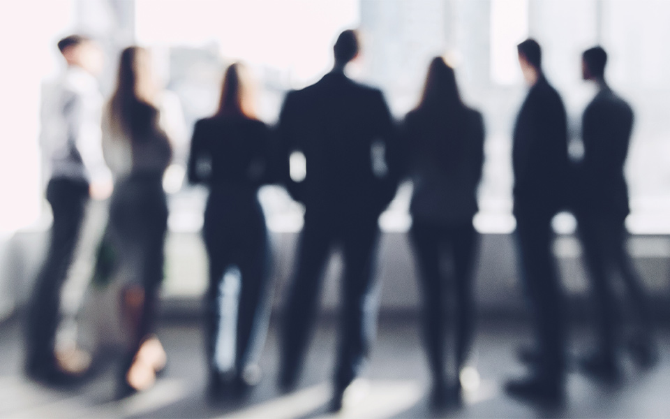 Blurred silhouettes of business professionals standing together in a modern office setting